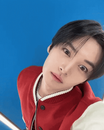 Young Man In Red Jacket Looking Up Against Blue Background GIF