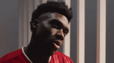 Young Man In Red Shirt Looks At Camera GIF