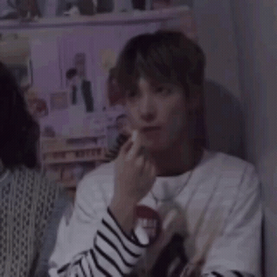 Young Man In Striped Shirt And Necklace Sitting GIF