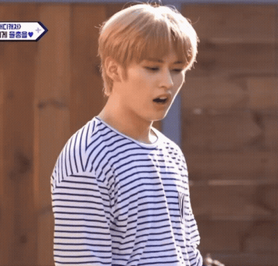 Young Man In Striped Shirt Standing Before Wooden Door GIF