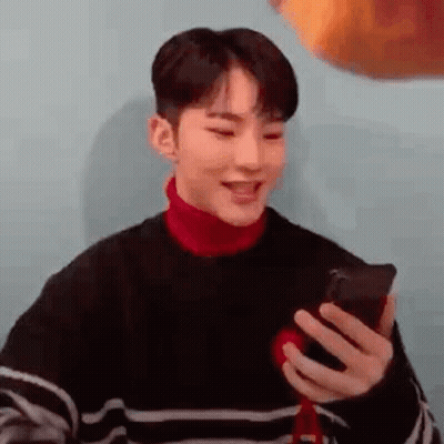 Young Man In Striped Sweater Holding Cell Phone GIF