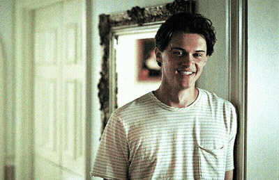 Young Man In Striped T-Shirt Smiling In Hallway GIF