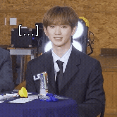 Young Man In Suit And Tie Sitting At Table GIF