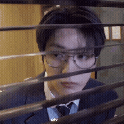 Young Man In Suit Looking Through Window GIF