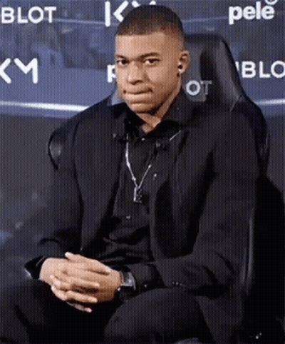Young Man In Suit Sitting With Hands Folded GIF