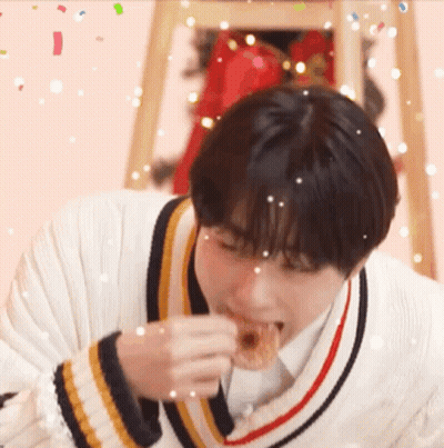 Young Man In Sweater Eating Donut With Confetti GIF