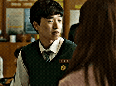 Young Man In Vest And Tie Looking At Woman In Classroom GIF