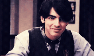 Young Man In Vest And Tie With M Badge GIF