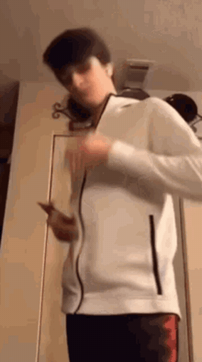 Young Man In White Jacket Holding Phone GIF