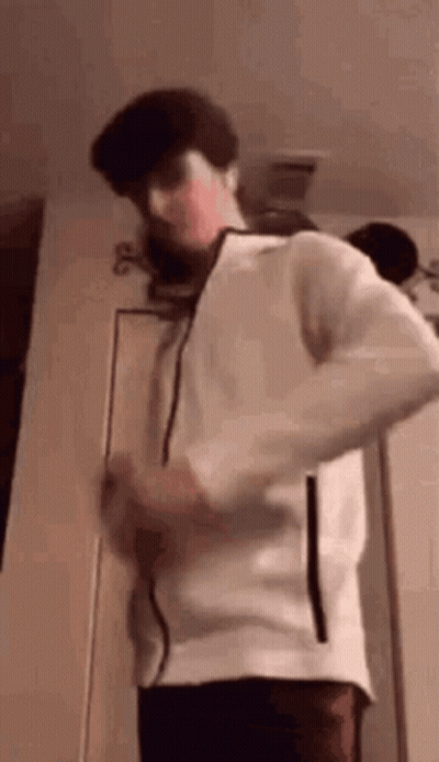 Young Man In White Jacket Standing In Front Of Door GIF