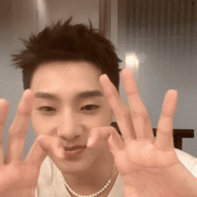 Young Man In White Shirt And Pearl Necklace Making Peace Sign GIF