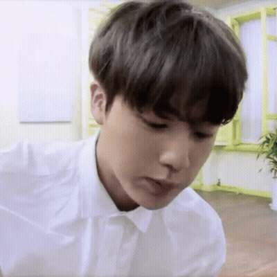 Young Man In White Shirt Sitting In Room With Plant GIF