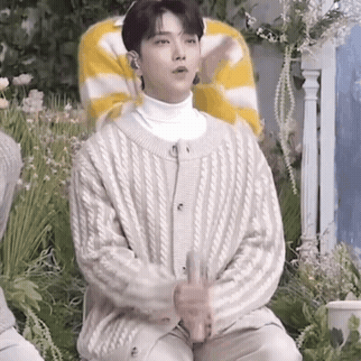 Young Man In White Sweater Holding Glass GIF
