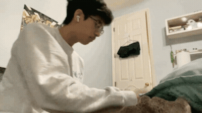 Young Man In White Sweater Laying On Bed GIF