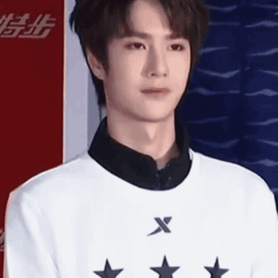 Young Man In White Sweater With Stars Against Red And Blue Wall GIF