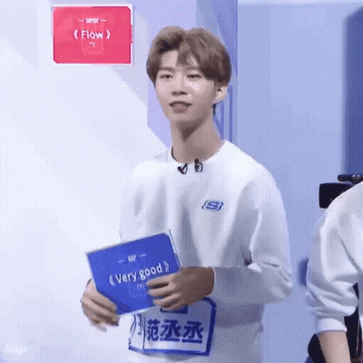 Young Man In White Sweatshirt Holding Blue Book GIF