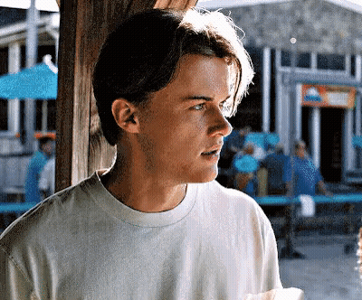 Young Man in White T-Shirt Holding Paper in Front of Building