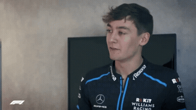 Young Man In Williams Racing Jacket Standing Before TV GIF