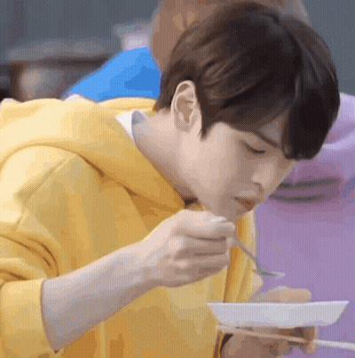 Young Man In Yellow Hoodie Eating With Chopsticks GIF