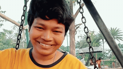 Young Man In Yellow Shirt Smiling On Swing GIF