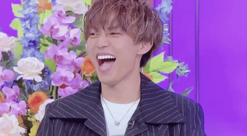 Young Man Laughing In Front Of Flowers GIF