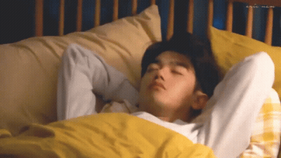Young Man Laying In Bed With Yellow Comforter GIF