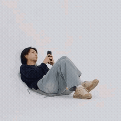 Young Man Laying On Floor Looking At Phone GIF