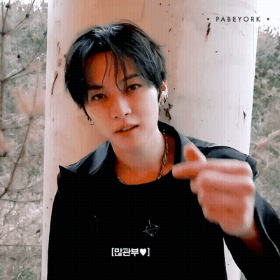 Young Man Leaning Against Pillar Making Heart With Fingers GIF