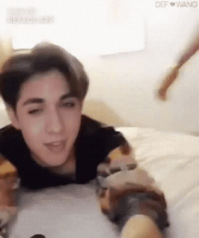 Young Man Lying On Bed Arms Outstretched GIF
