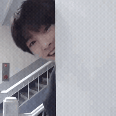 Young Man Peeking Behind Wall GIF