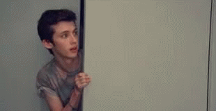 Young Man Peeking From Door Holding White Board GIF