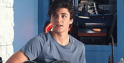 Young Man Playing Guitar In Room With Lamp GIF