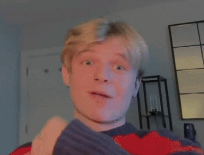 Young Man Pointing Up In Red And Blue Sweater GIF