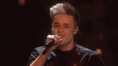 Young Man Singing Into Microphone On Stage GIF