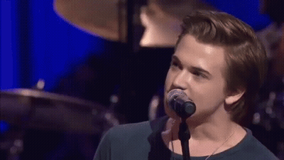 Young Man Singing Into Microphone On Stage GIF
