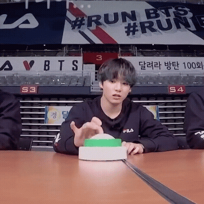 Young Man Sitting At Table With Run BTS Sign GIF