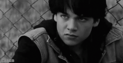 Young Man Sitting By Chain Link Fence GIF