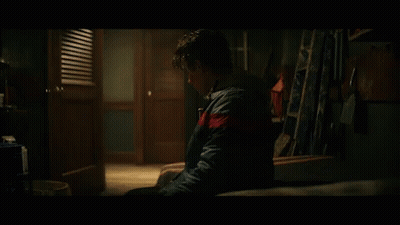 Young Man Sitting In Dark Room With Ladder GIF