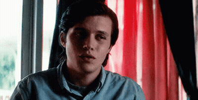 Young Man Sitting In Front Of Red Curtain Window GIF
