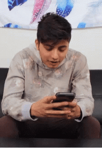 Young Man Sitting On Couch Looking At Phone GIF
