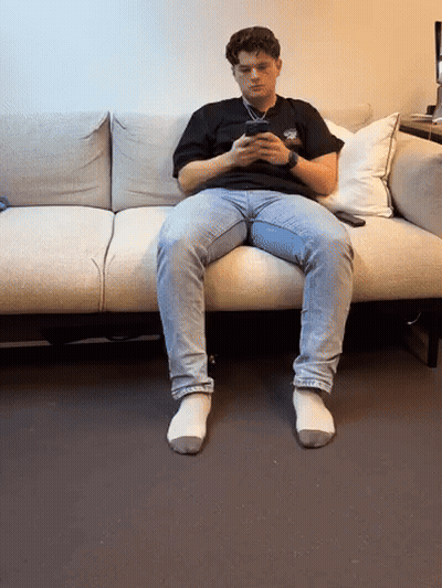 Young Man Sitting On Couch Looking At Phone GIF