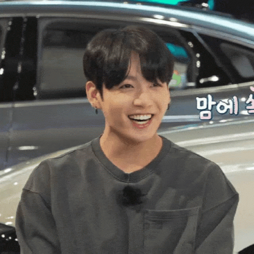 Young Man Smiling By Car With Foreign Writing GIF