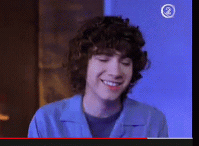 Young Man Smiling In Front Of Blue Wall With Number 2 GIF