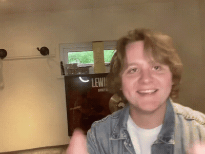 Young Man Smiling In Front Of Lewis Sign GIF