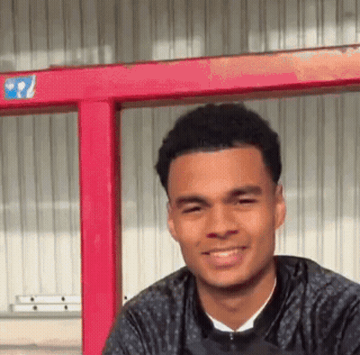 Young Man Smiling In Front Of Red Railing GIF