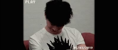 Young Man Smiling On Red Couch GIF