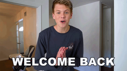 Young Man Standing Before Welcome Back Sign GIF