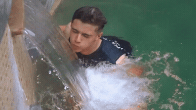 Young Man Swimming In Pool With Waterfall GIF