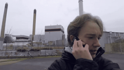 Young Man Talking On Cell Phone In Front Of Factory GIF