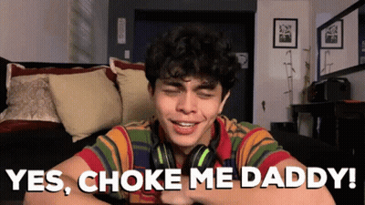 Young Man Wearing Headphones Sitting On Couch Says Yes Choke Me Daddy GIF